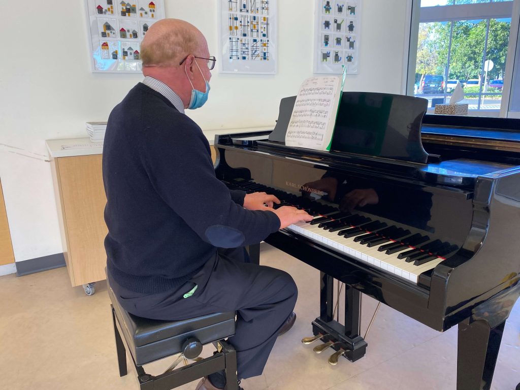 Mr David Docwra playing the piano as parents drink their coffee