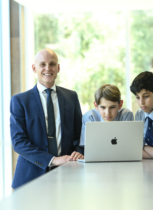 Male teacher helping student on their laptop